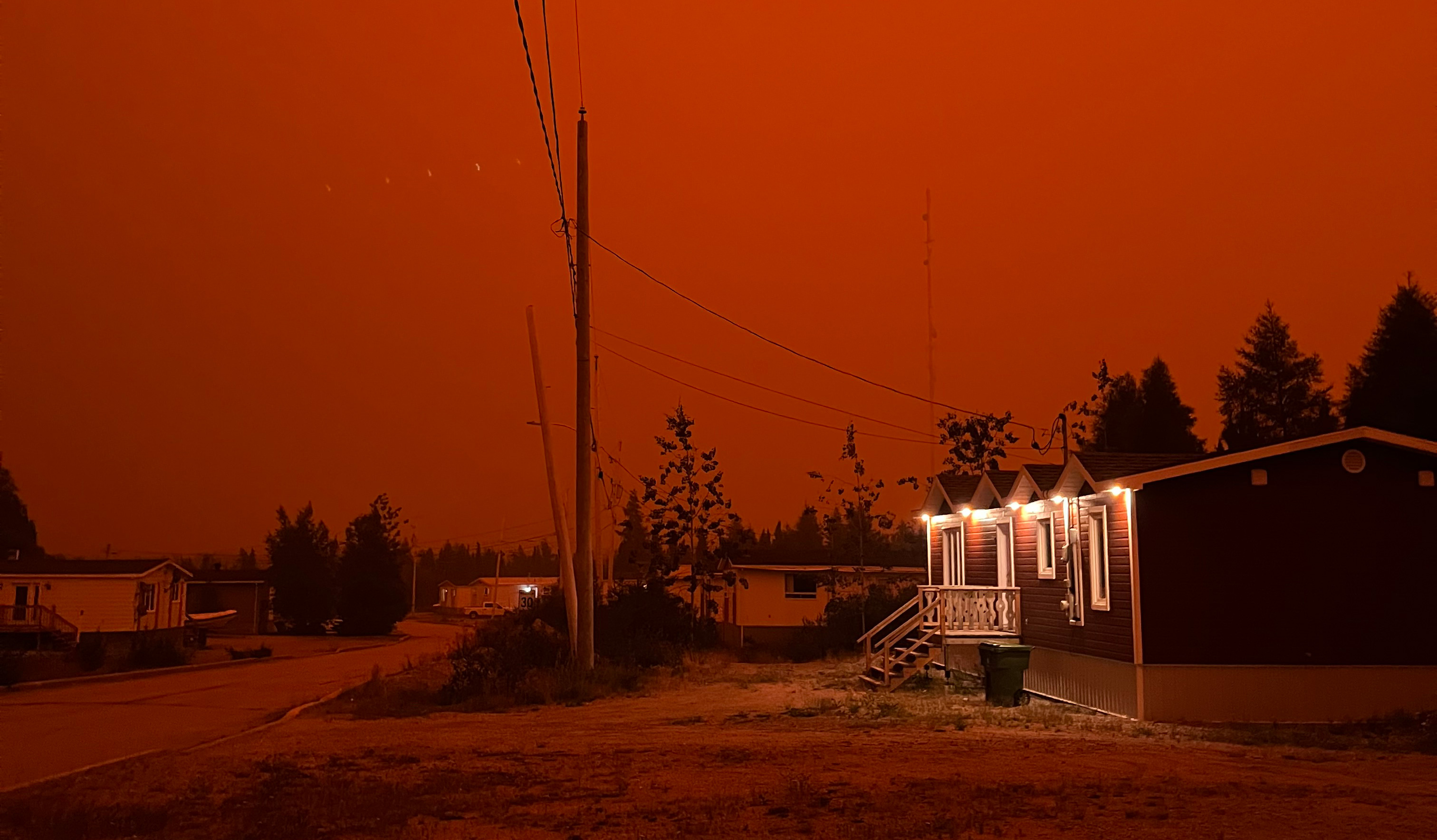 Orange wildfire smoke clouds a community in La Grande Rivière, Quebec.
