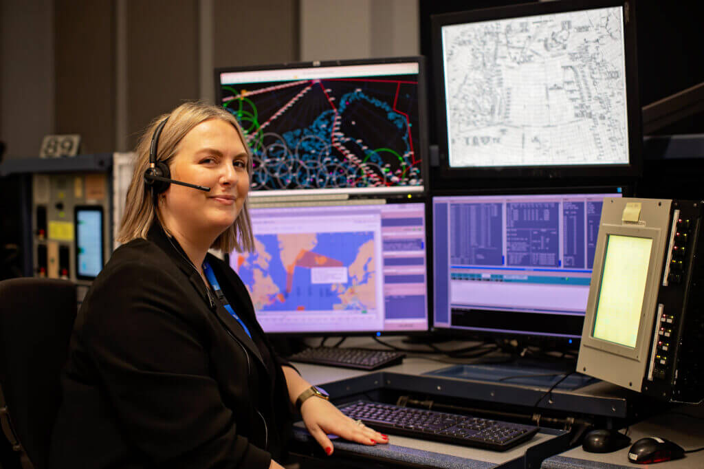 Une professionnelle du service de la circulation aérienne portant un casque surveille plusieurs écrans affichant des informations radar et de vol.