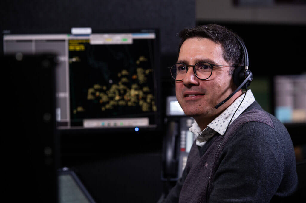 Un professionnel du service de la circulation aérienne portant un casque surveille les écrans radar pendant son quart de travail dans un centre d'information de vol.