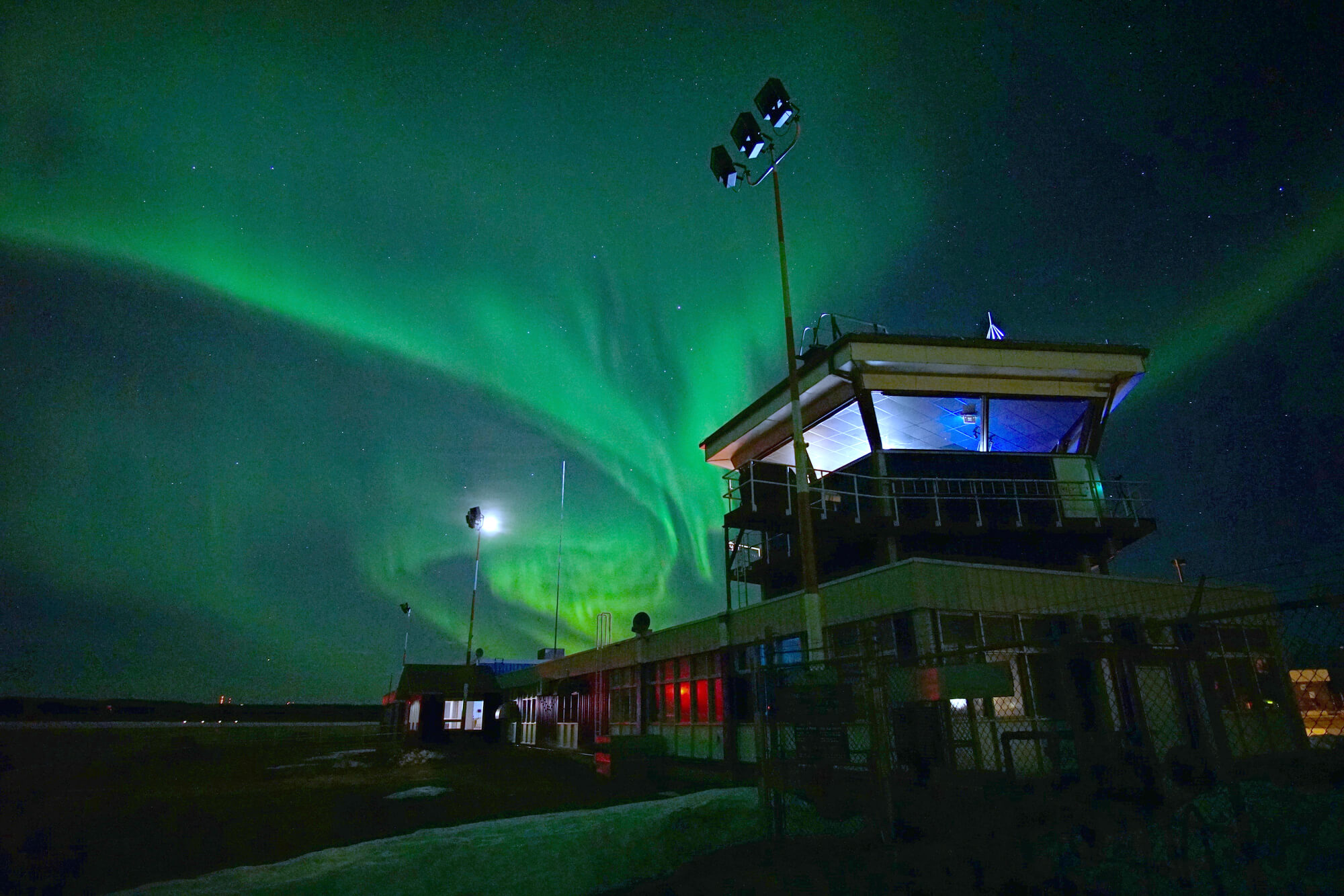 Les aurores boréales illuminent le ciel nocturne au-dessus d’un bâtiment. 