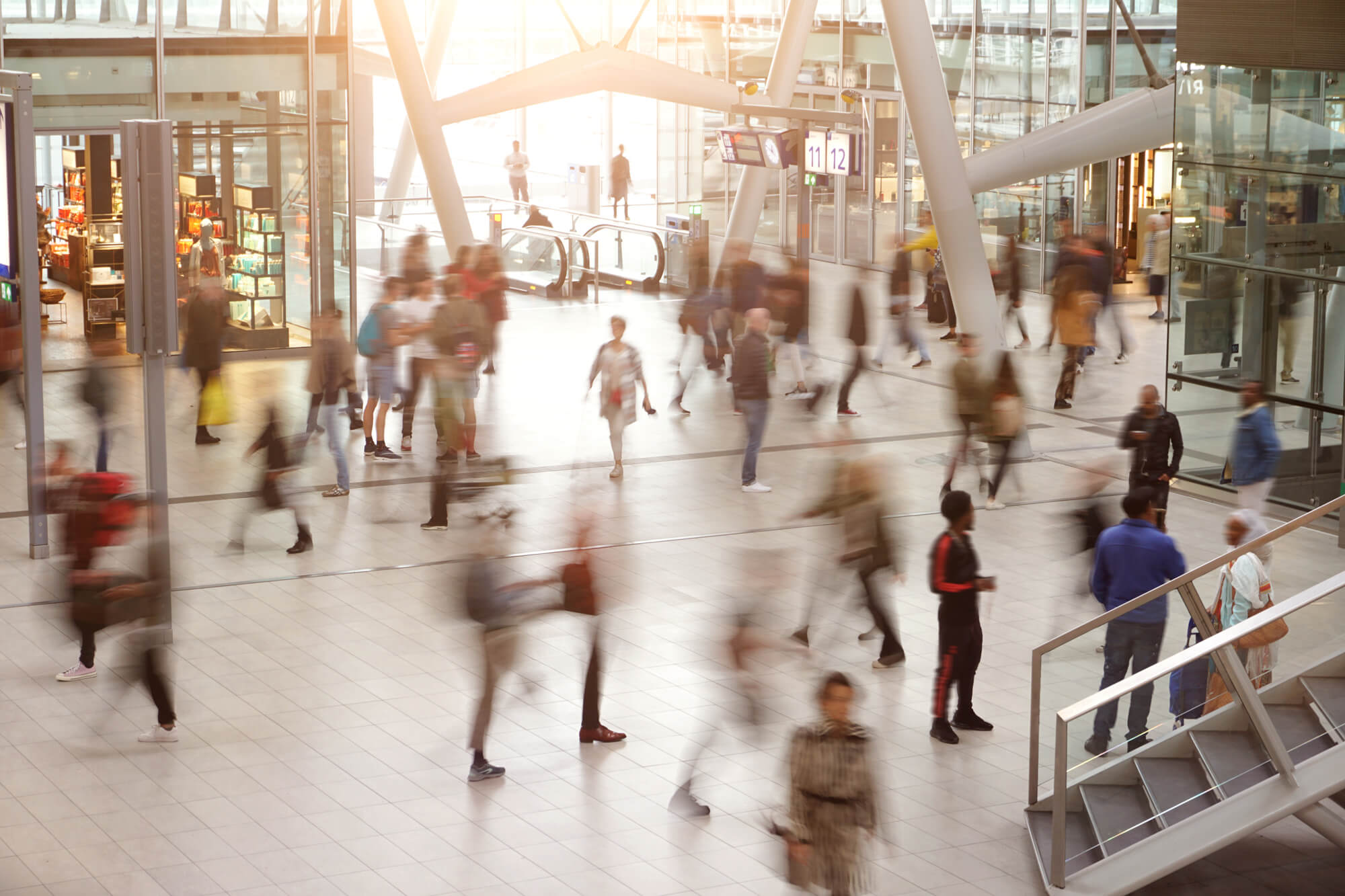 A busy airport terminal with blurred motion of people walking in various directions, reflecting the fast-paced environment of travel.