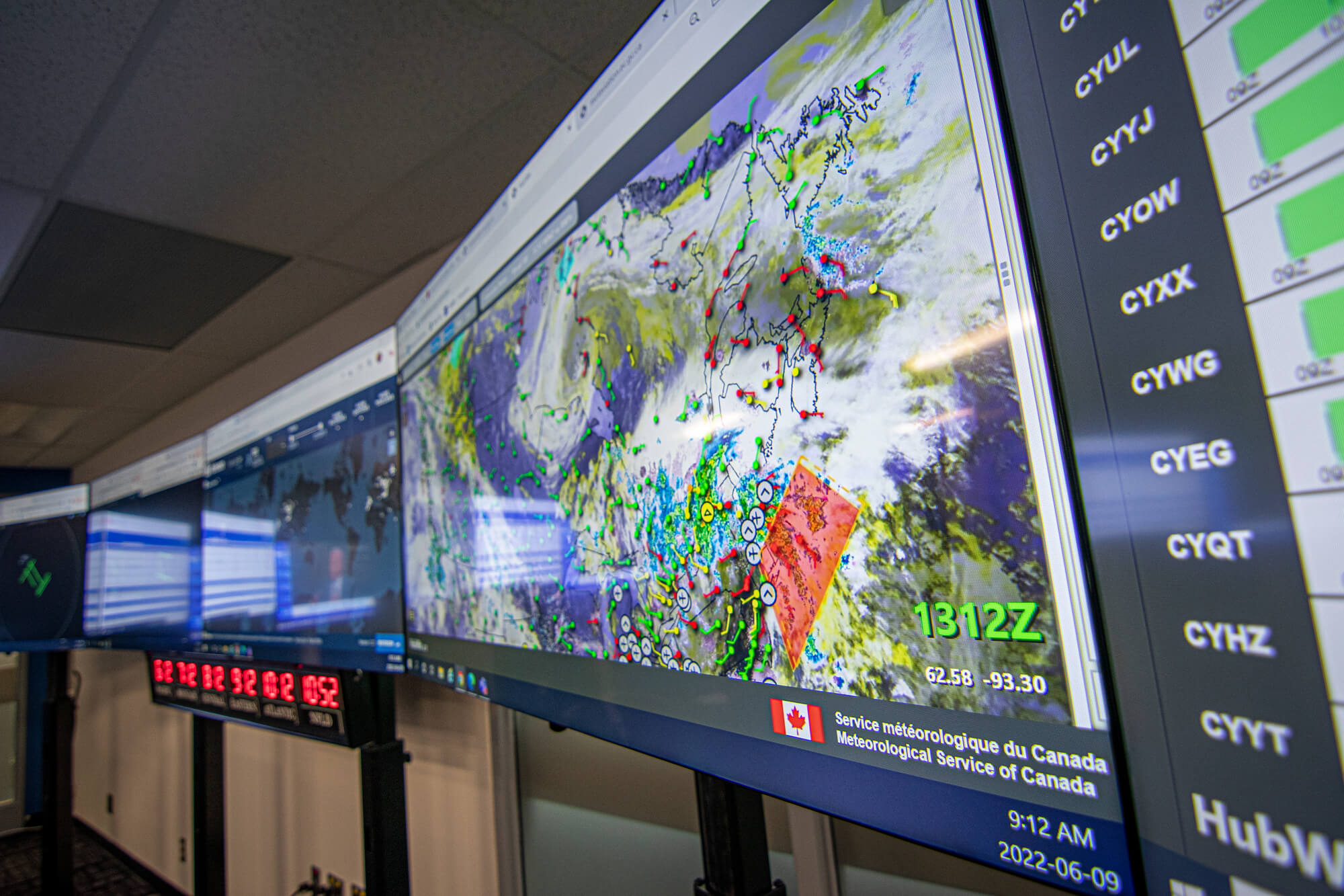A bank of computer screens displays weather maps and aviation data.